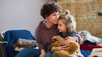 A parent and child sitting on a cot.