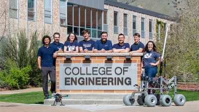 Students posing next to a robotic rover and a sign that says "College of Engineering."