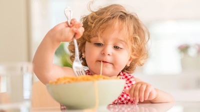A toddler eating spaghetti.