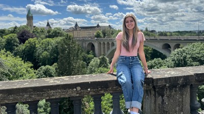 A woman sits on a bridge overlooking a college campus in Spain.