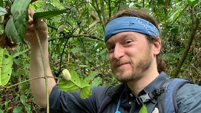 Jerry Schneider holding a plant in a jungle.
