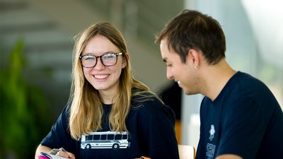 A woman smiles while conversing with a man at a table.