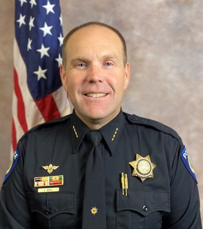 Police officer poses for a photo in uniform.