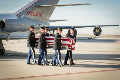U.S. military members carry a flag-draped casket from an airplane.