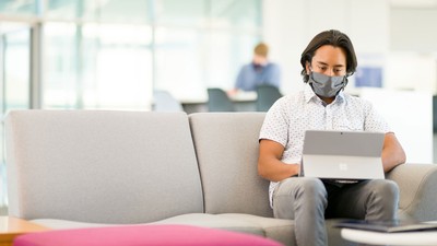 student sitting on a couch with his laptop.