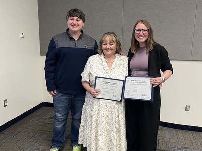 Three people pose for a photo holding certificates.