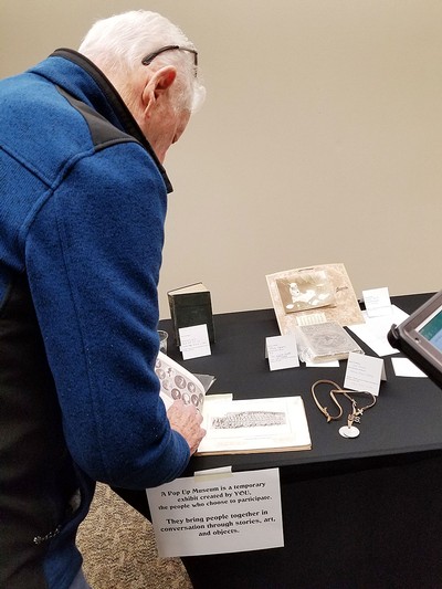 An elderly man examines objects at a "We Will Remember Them" World War One roadshow.