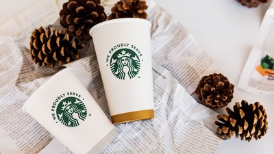 Starbucks coffe cups are displayed with decorative crumpled paper and pinecones.