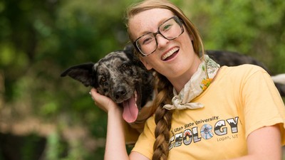 A Utah State University Student poses with a dog.