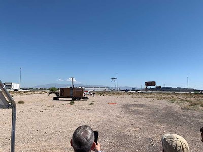 a drone takes flight as onlookers watch.