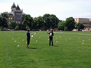 two Extension workers and water catch cups on USU's Quad