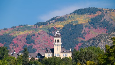 Old Main is seen against a background of fall colors on the hillside.