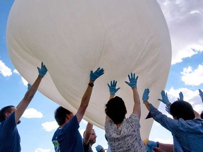 students hold up a balloon filled with air.