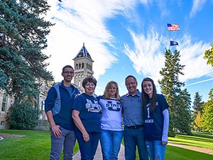 a family in Aggie gear on the USU campus outside Old Main