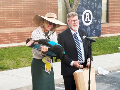 A woman displays a gift and smiles.