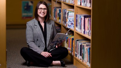 Kessa Roberts in a library reading a comic book.