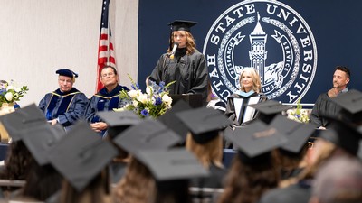 A speaker in regalia addresses a graduation ceremony.
