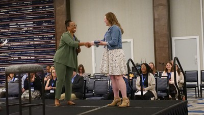 Two women shaking hands on stage while accepting award