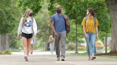 USU students walking near the Quad and wearing masks.