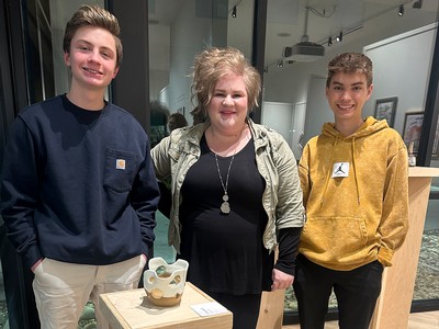 Three people stand in an art gallery and pose for a photo.