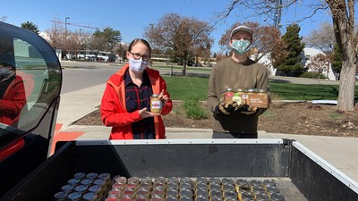 two students wearing masks loading canned food into a truck.