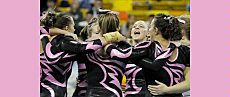 Aggie gymnasts in pink trimmed uniforms