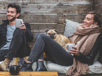 a man and woman relaxing with a cup of coffee and their dog