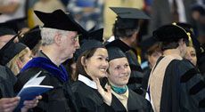 Two USU Graduates wave to onlookers