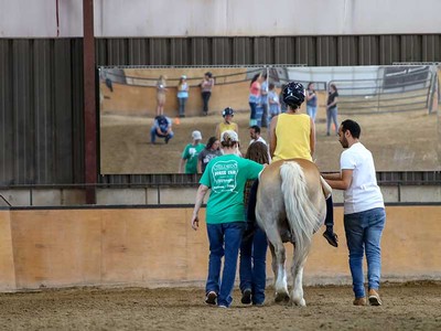 two people assist a person on a horse.