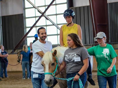 people gather around a person riding a horse.