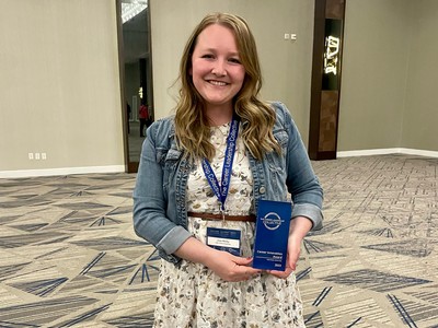 Woman poses with an award plaque