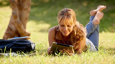 girl studying on her tablet in the grass.
