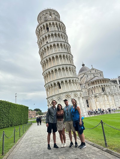 A family poses for a photo in front of the Leaning Tower of Pisa