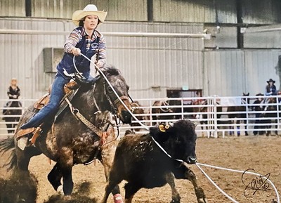 USU Rodeo Club member roping a cow in the arena.