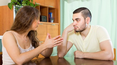a man and a woman sitting at a table and talking.
