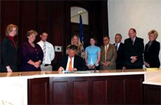 A large group witness the signing of SB 241