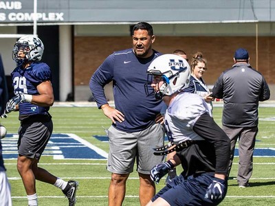 Linebackers coach Justin Ena with players on the field.