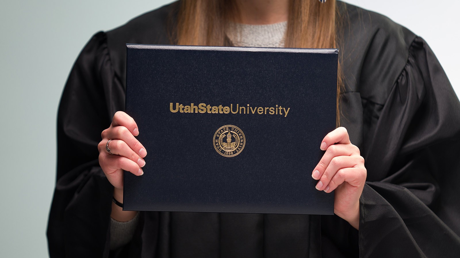 Hands holding a USU diploma.