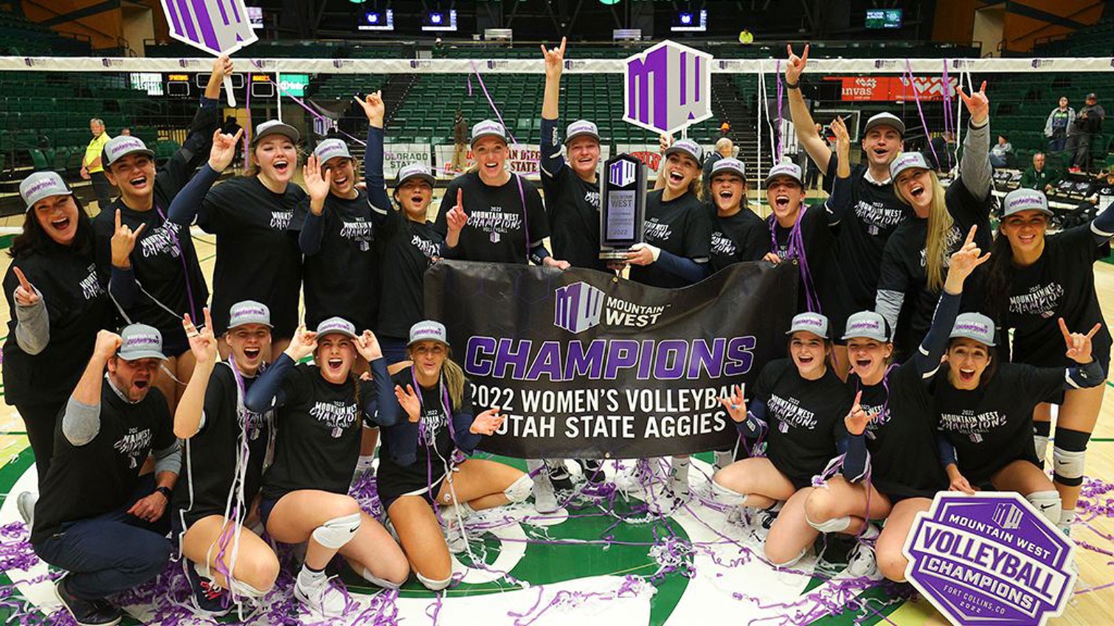 The USU volleyball team holding a banner reading: "Mountain West Champions."
