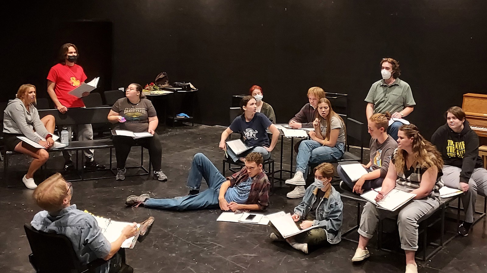 Students rehearsing a play in a black room.