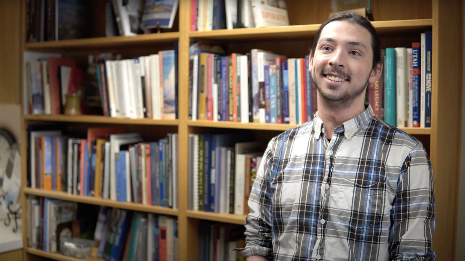 David Suisse stands in front of an office bookshelf.