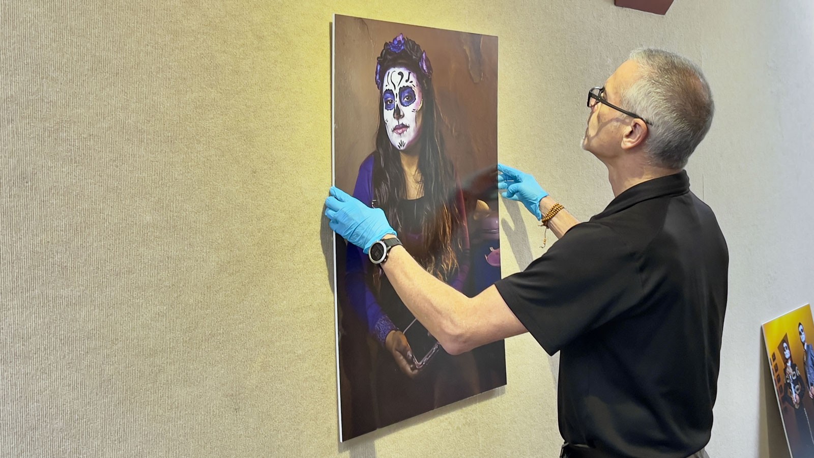 J.P. Spicer-Escalante hanging a photograph of a woman with Day of the Dead skull facepaint.