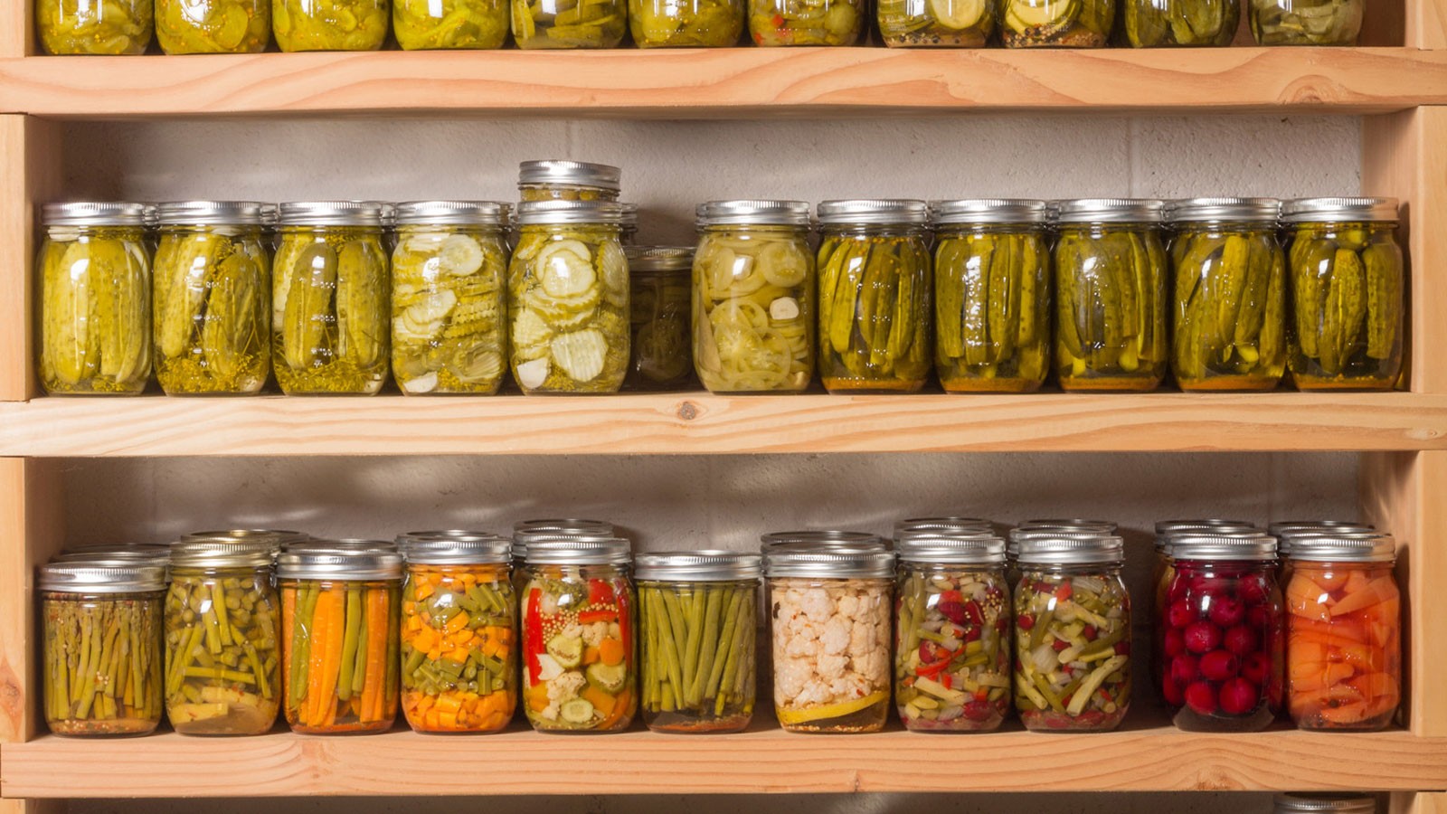 A shelf holds jars of pickled vegetables.