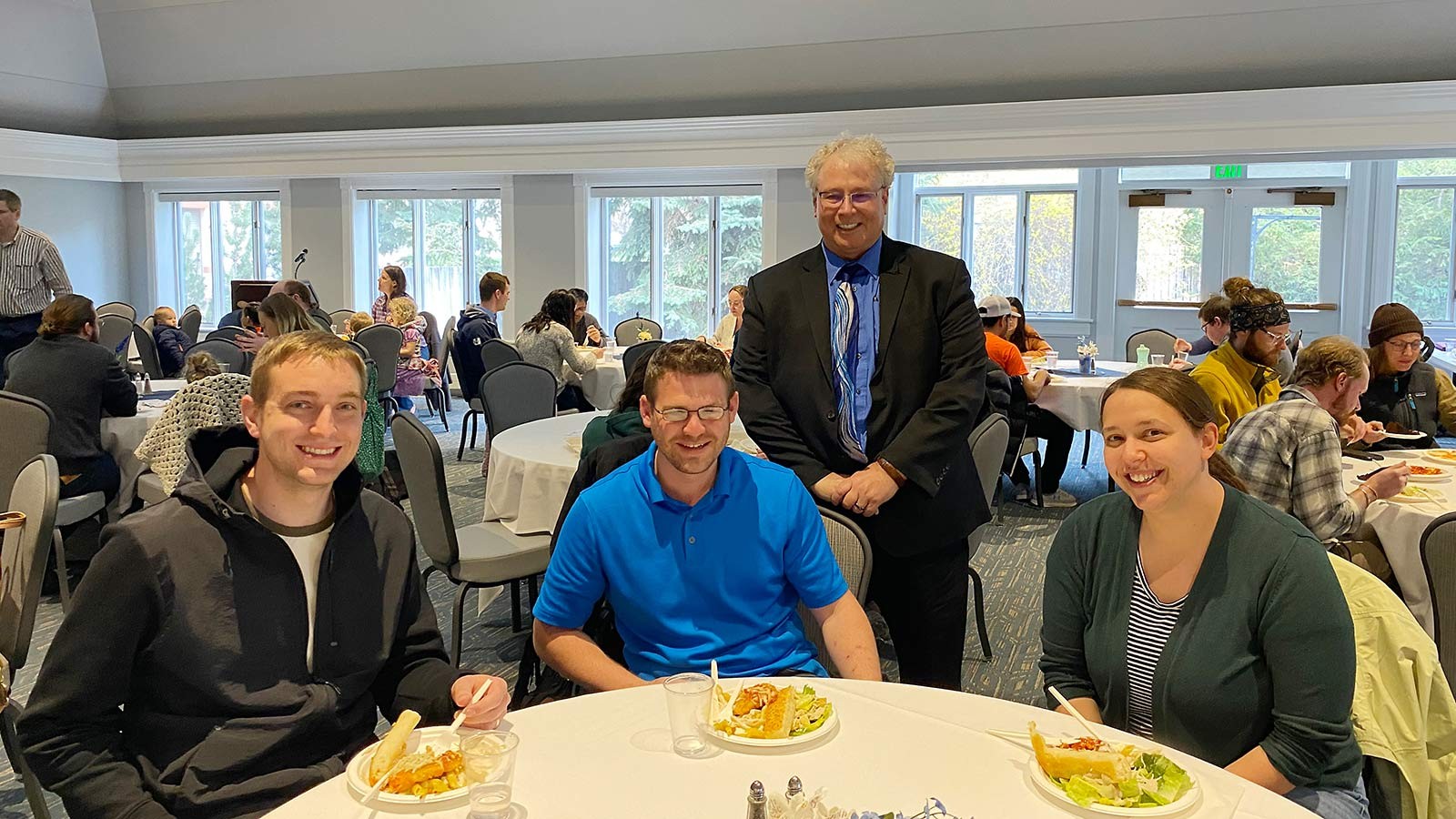 D. Richard Cutler poses for a picture with students during a dinner event.