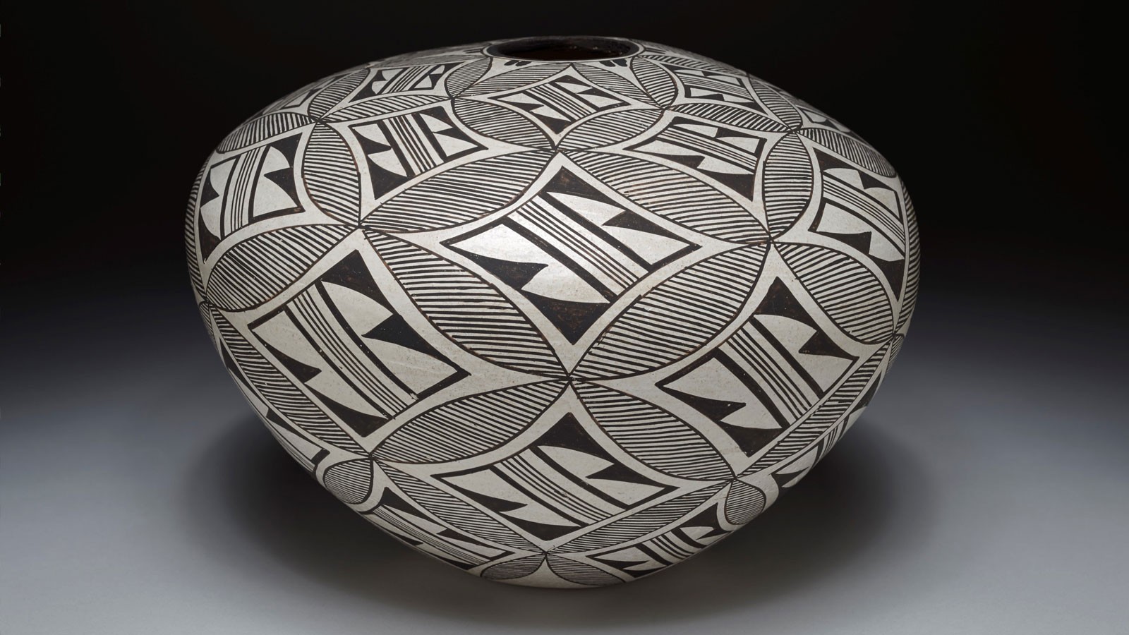 A round piece of pottery shows an intricate black-and-white pattern.