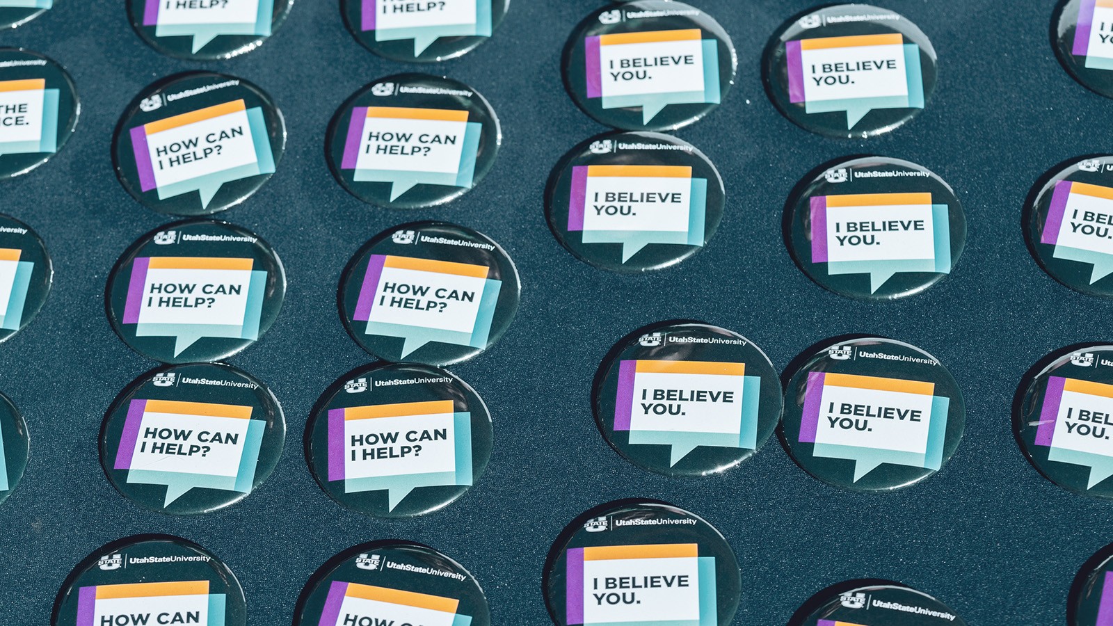 Pinback buttons arranged on a table state "I believe you" and "how can I help?"
