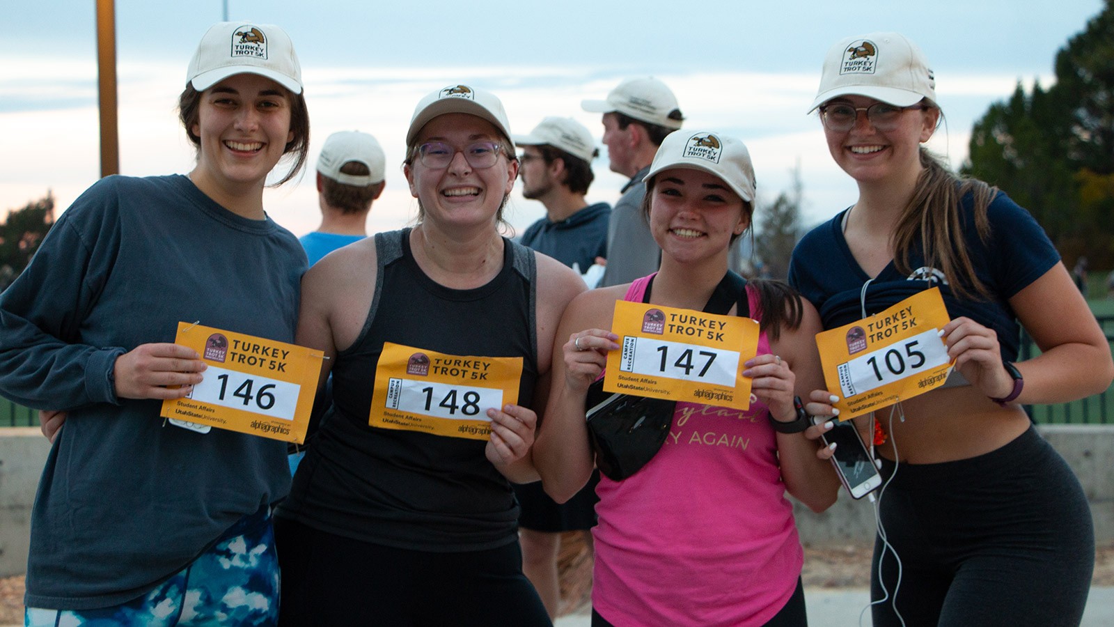Runners holding up their race entry numbers for a photo.