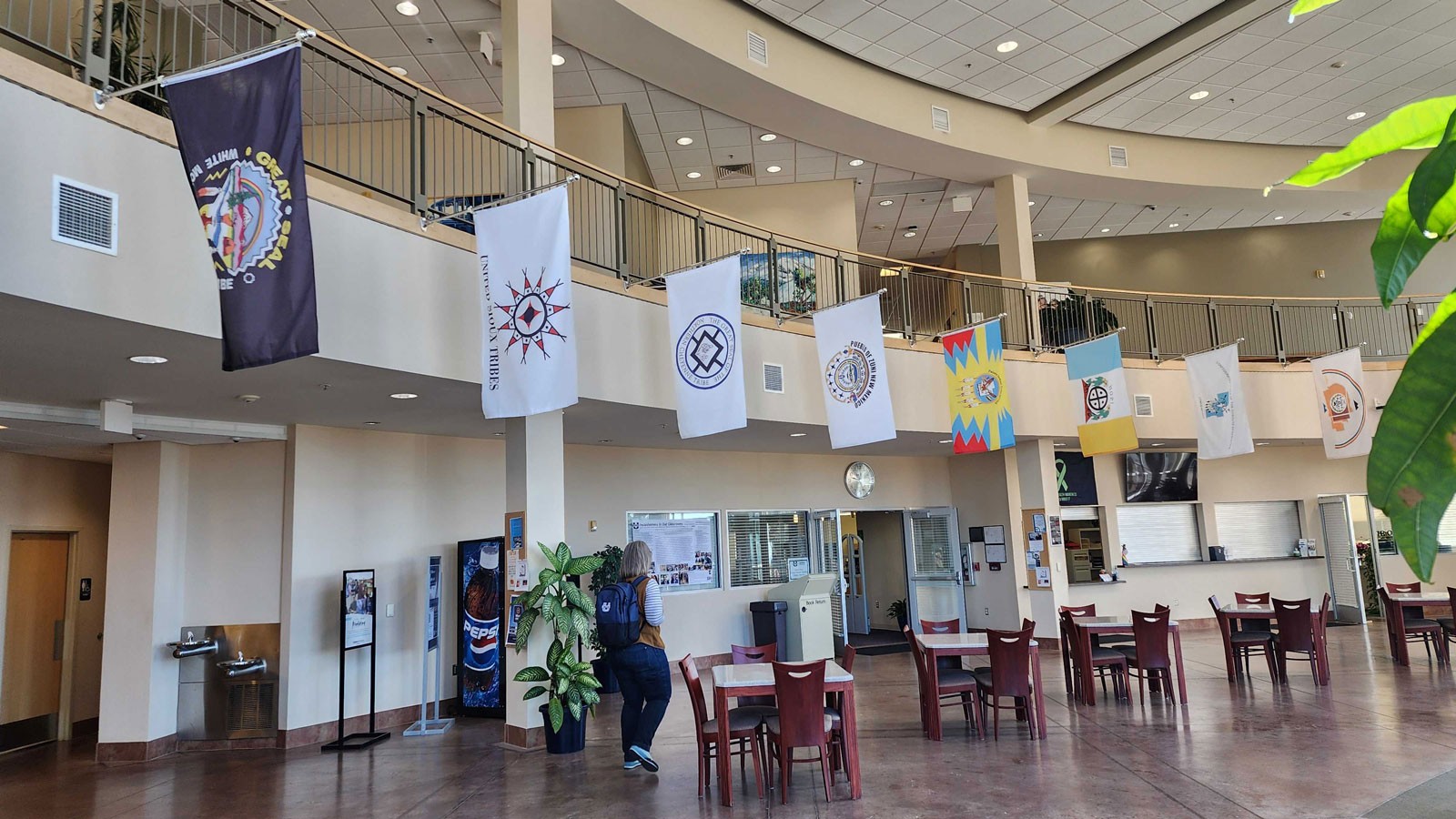 Several Native American flags hanging in a building lobby.