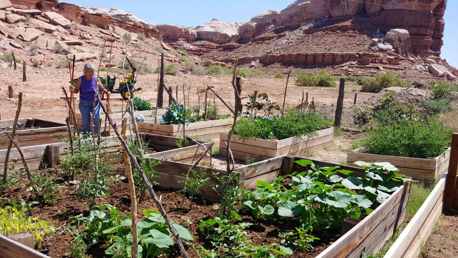 A woman works on a garden among redrock formations in Southern Utah.