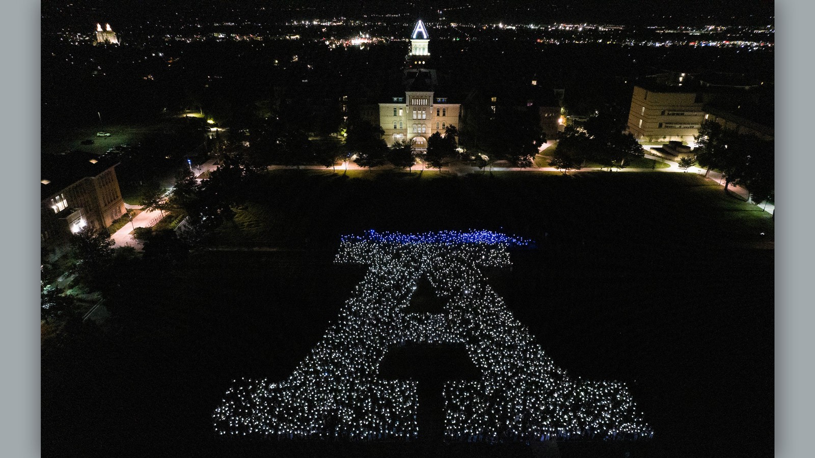 An aerial view of students holding lanterns in the shape of the letter A.